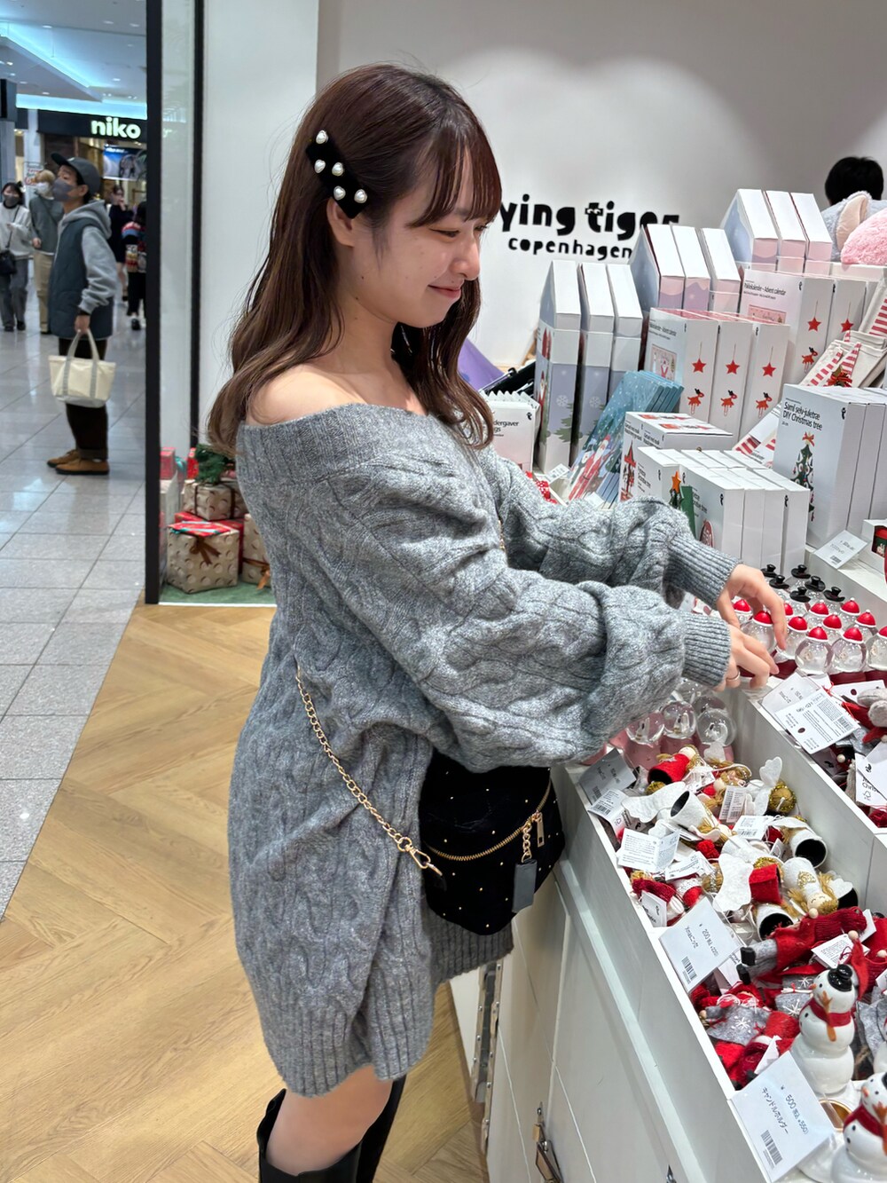 グレー系のワンピース、ブラック系のショルダーバッグ、ブラック系のブーツを着用したレディースの秋コーディネートの3枚目の写真