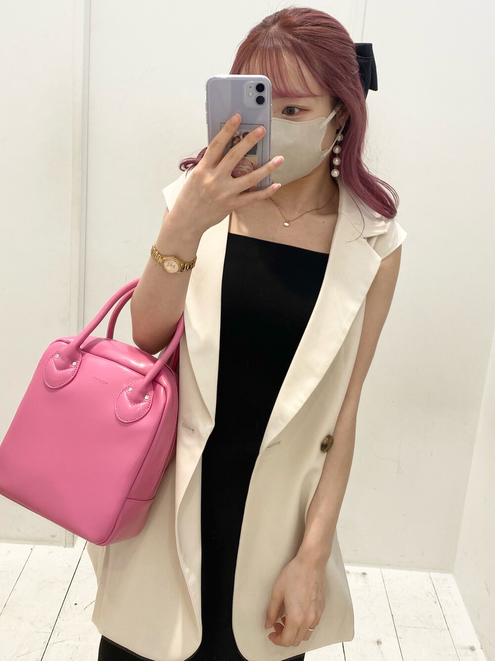 ホワイト系のベスト、ブラック系のワンピース、ピンク系のショルダーバッグを着用したレディースの夏コーディネートの2枚目の写真