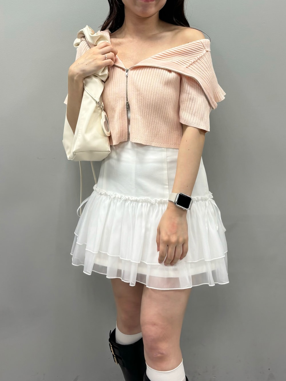 ピンク系のニット/セーター、ホワイト系のスカート、ブラック系のブーツを着用したレディースの春コーディネートの4枚目の写真