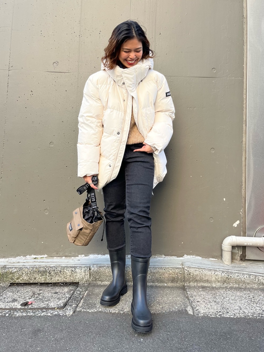 ブラック系のデニムパンツ、ベージュ系のニット/セーター、ブラック系のレインシューズを着用したレディースの冬コーディネートの3枚目の写真