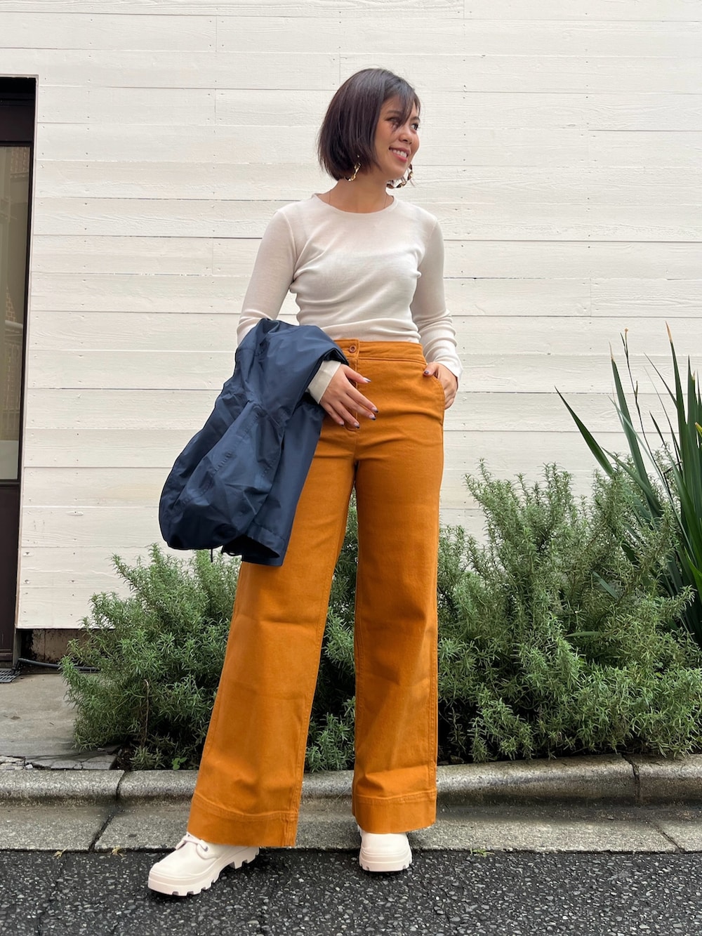 オレンジ系のその他パンツ、ホワイト系のスニーカー、ホワイト系のTシャツ/カットソーを着用したレディースの秋コーディネートの3枚目の写真