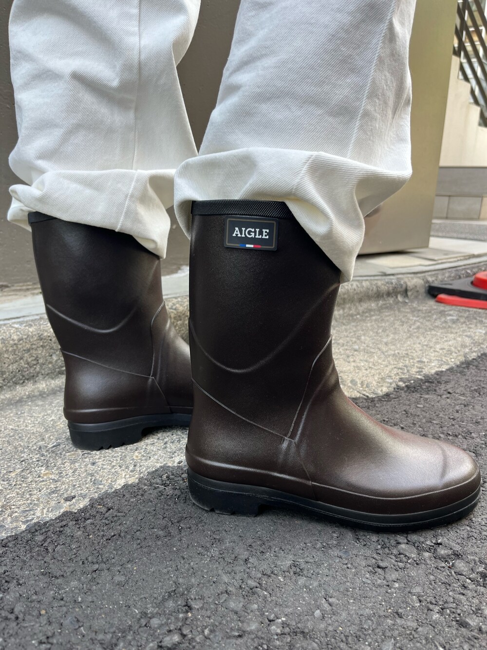 ブラウン系のニット/セーター、ホワイト系のサロペット/オーバーオール、ブラウン系のレインシューズを着用したレディースの秋コーディネートの4枚目の写真