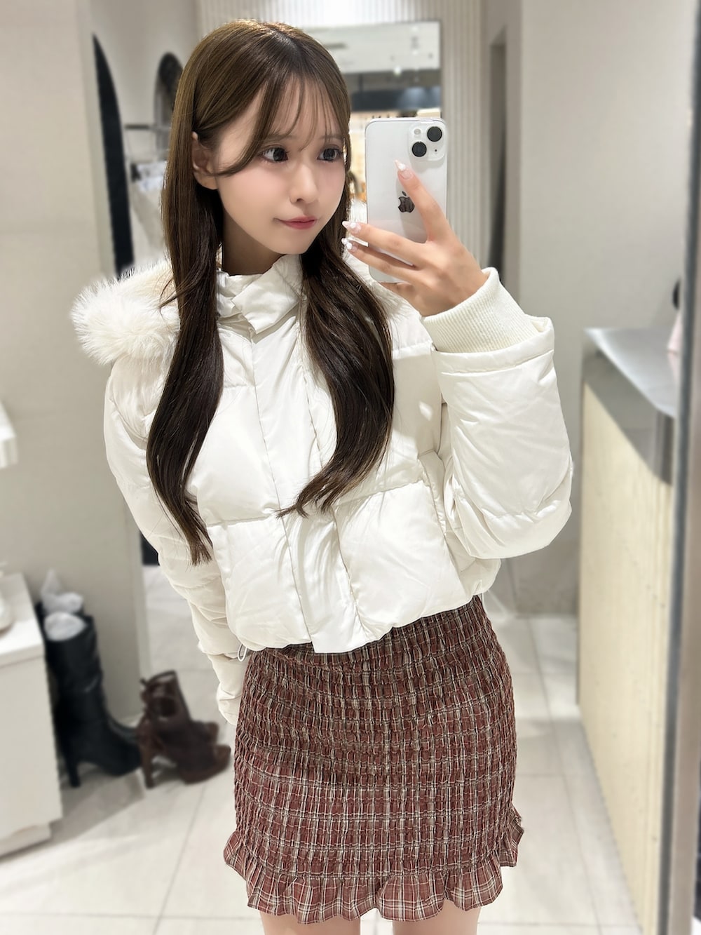 レッド系のワンピース、ホワイト系のブルゾン、ブラウン系のブーツを着用したレディースの秋コーディネートの7枚目の写真