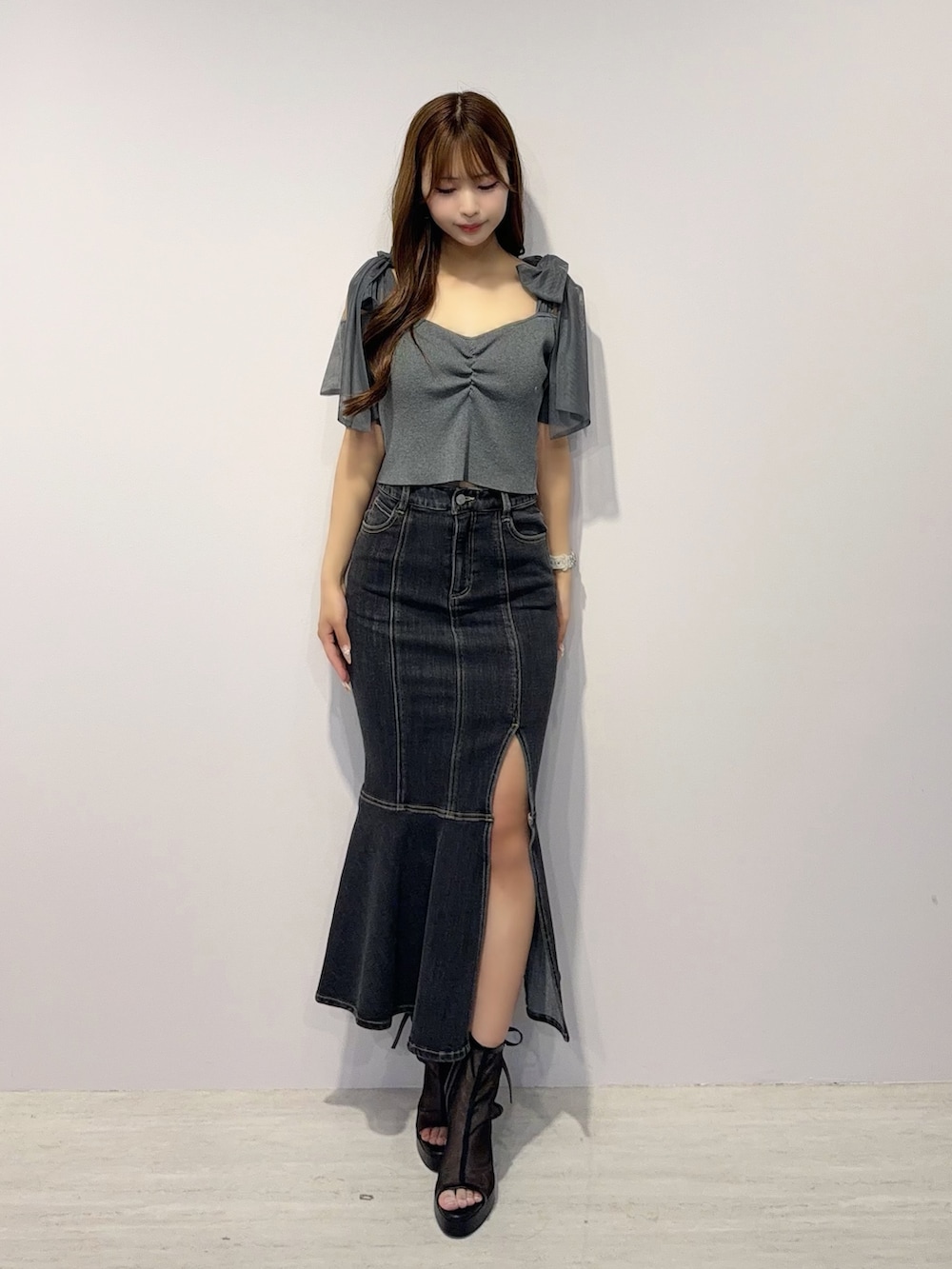 ブラック系のデニムスカート、グレー系のTシャツ/カットソー、ブラック系のサンダルを着用したレディースの春コーディネートの2枚目の写真