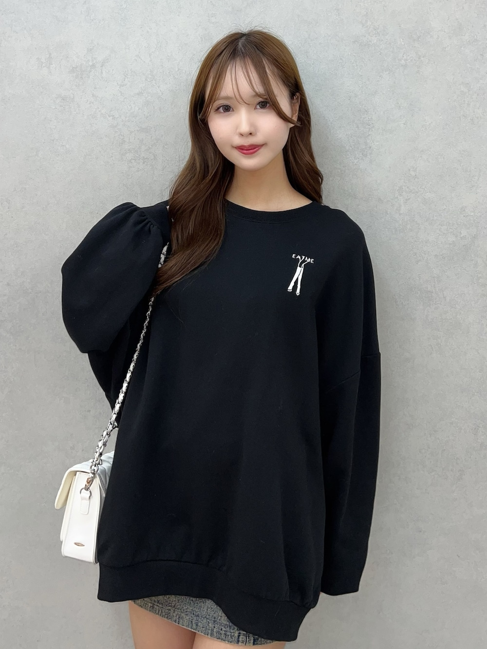 ブラック系のスウェット、ブルー系のデニムスカート、ホワイト系のショルダーバッグを着用したレディースの秋コーディネートの4枚目の写真