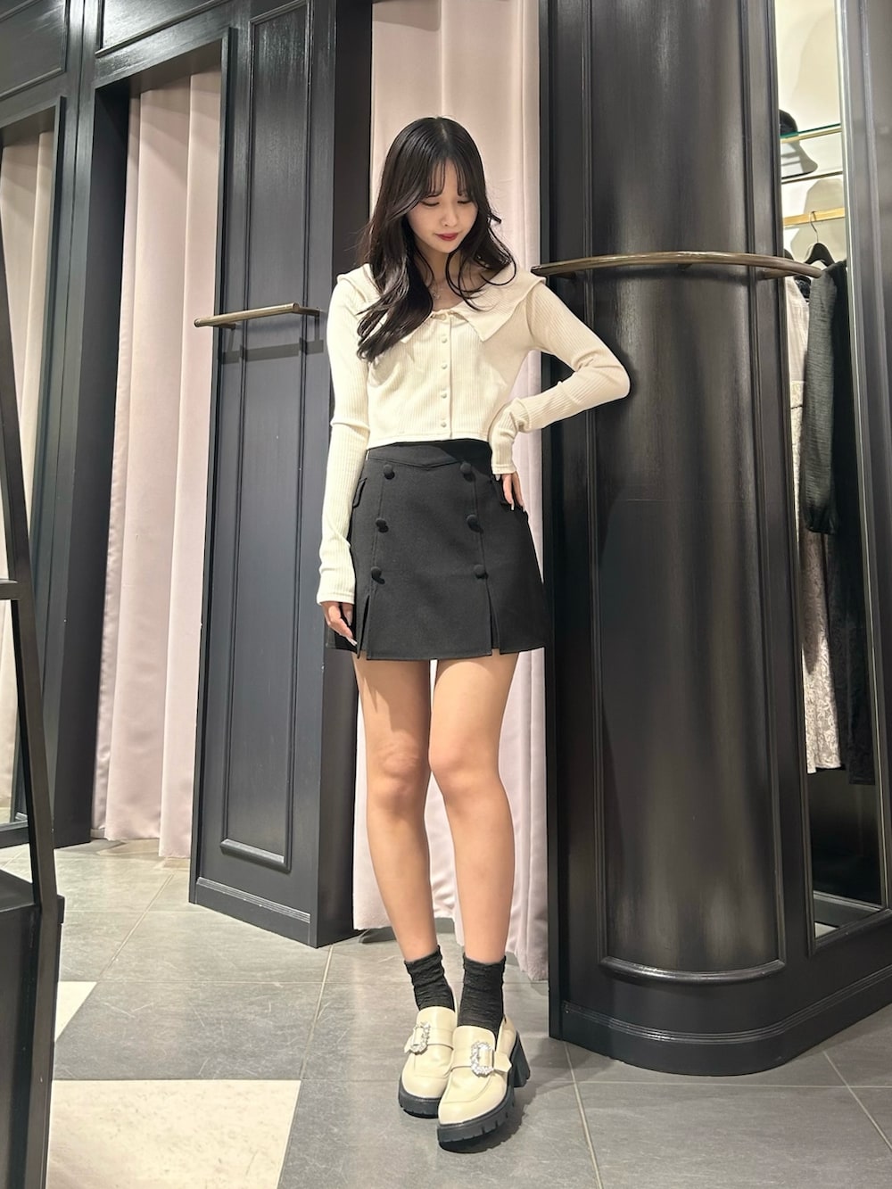 ブラック系のスカート、ホワイト系のTシャツ/カットソー、ベージュ系のローファーを着用したレディースの冬コーディネートの3枚目の写真