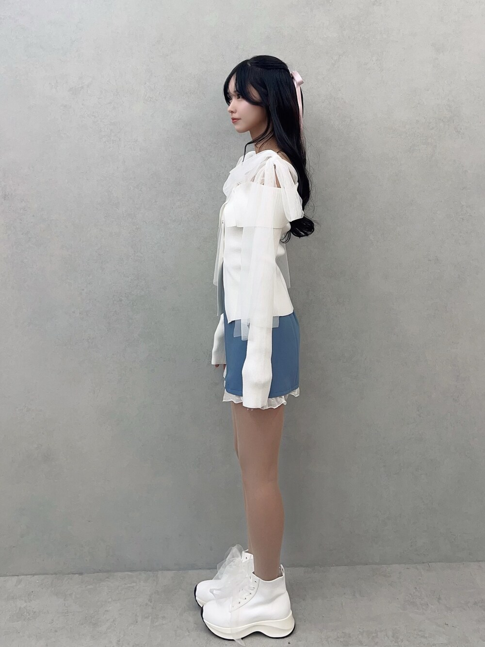 ホワイト系のニット/セーター、ブルー系のスカート、ホワイト系のブーツを着用したレディースの冬コーディネートの3枚目の写真