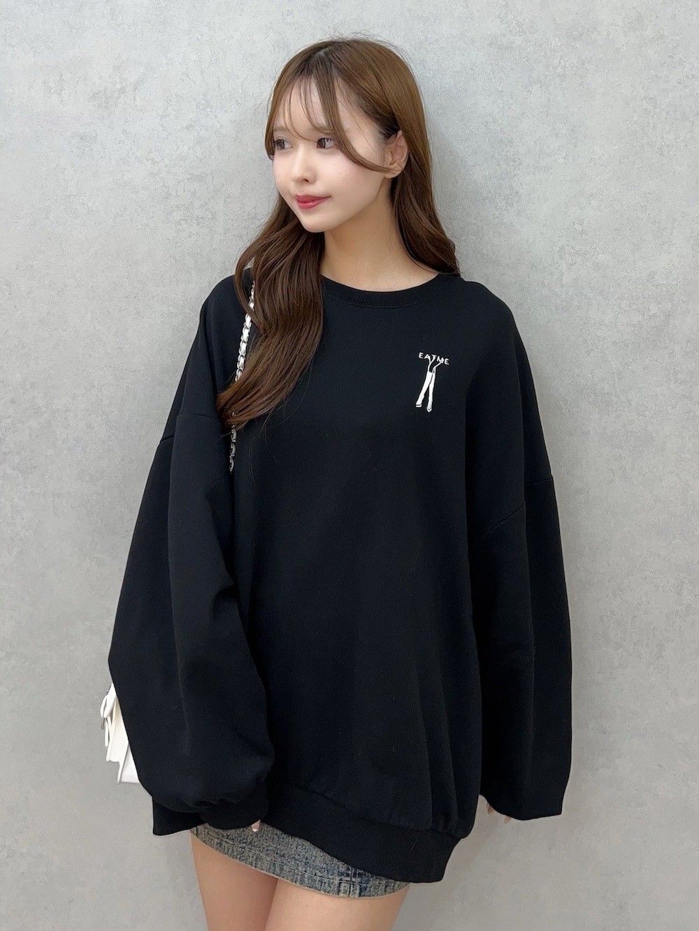 ブラック系のスウェット、ブルー系のデニムスカート、ホワイト系のショルダーバッグを着用したレディースの秋コーディネートの5枚目の写真