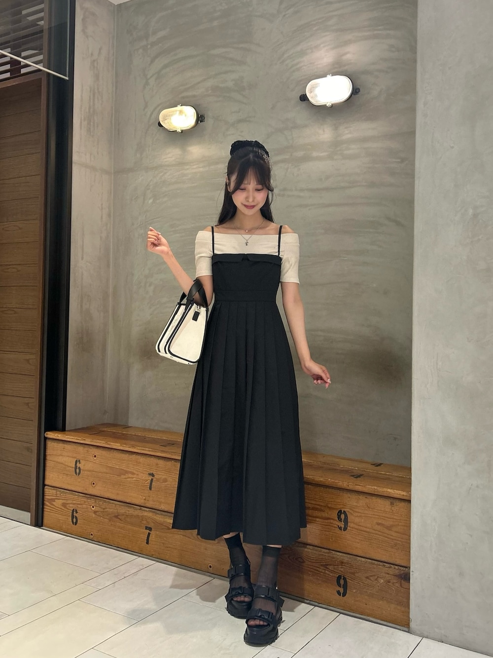 ブラック系のワンピース、ホワイト系のショルダーバッグ、ブラック系のサンダルを着用したレディースの春コーディネートの3枚目の写真