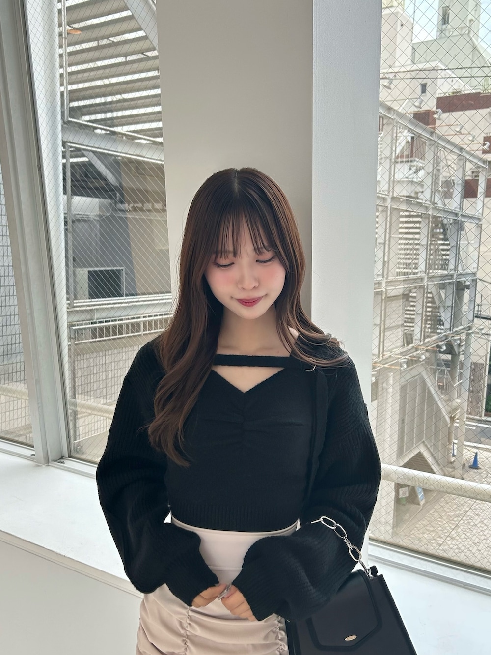 ベージュ系のスカート、ブラック系のニット/セーター、ブラック系のショルダーバッグを着用したレディースの秋コーディネートの2枚目の写真