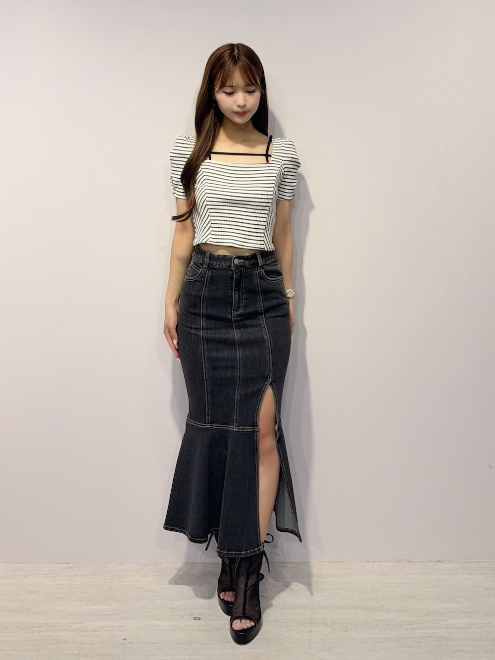 ブラック系のデニムスカート、その他のTシャツ/カットソー、ブラック系のサンダルを着用したレディースの春コーディネートの2枚目の写真