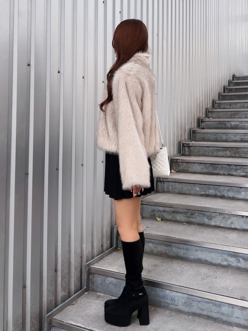 ベージュ系のブルゾン、ブラック系のワンピース、ブラック系のブーツを着用したレディースの冬コーディネートの3枚目の写真