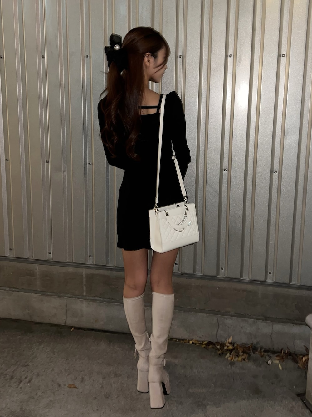 ブラック系のワンピース、ホワイト系のハンドバッグ、ホワイト系のブーツを着用したレディースの冬コーディネートの4枚目の写真