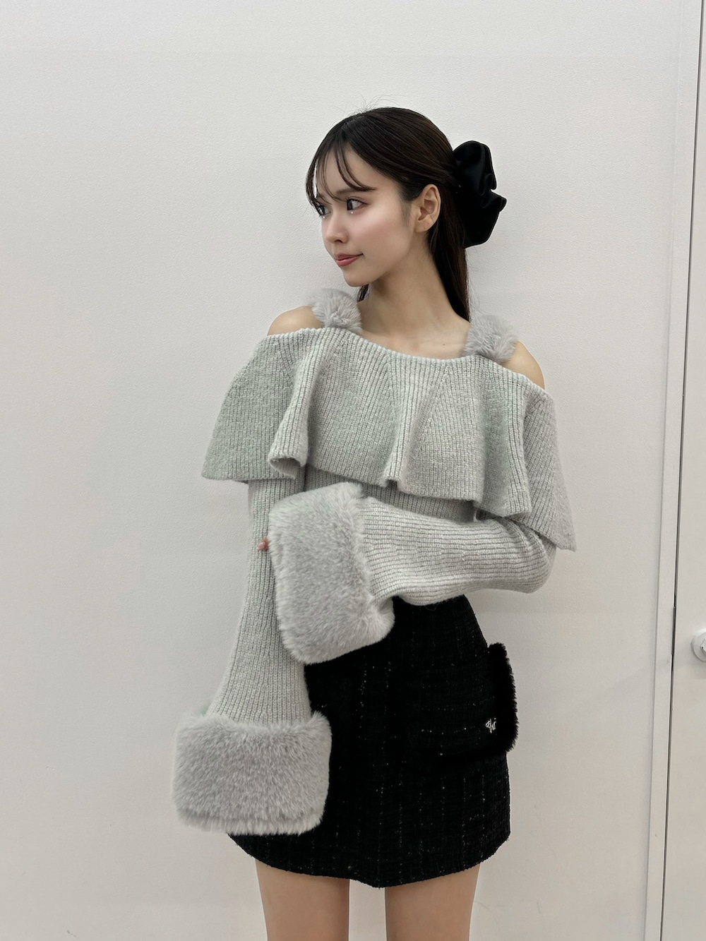 グレー系のニット/セーター、ブラック系のスカート、ブラック系のブーツを着用したレディースの秋コーディネートの4枚目の写真