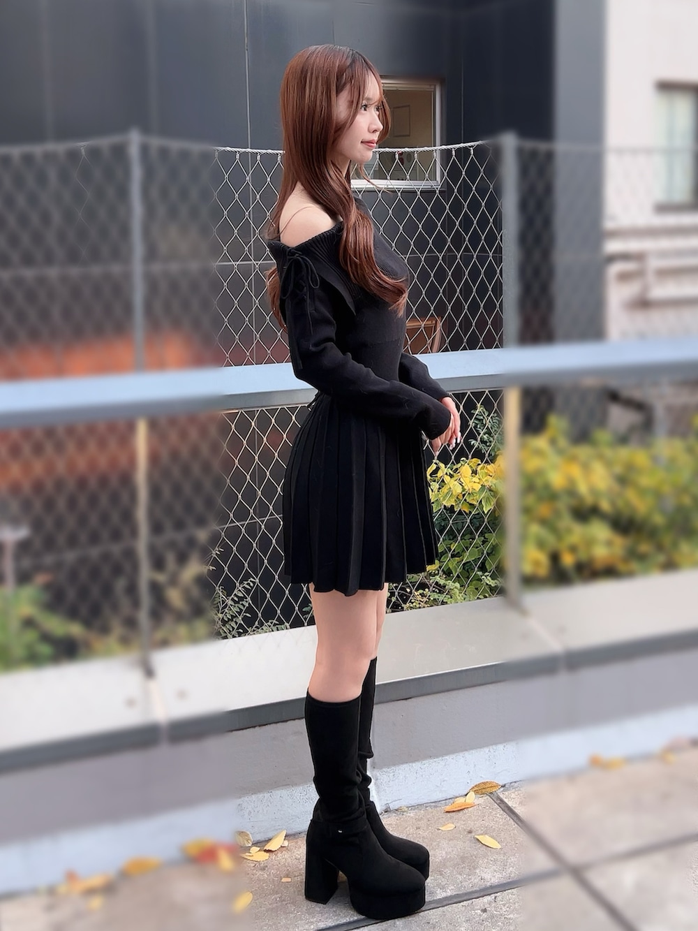 ブラック系のワンピース、ホワイト系のハンドバッグ、ブラック系のブーツを着用したレディースの冬コーディネートの3枚目の写真