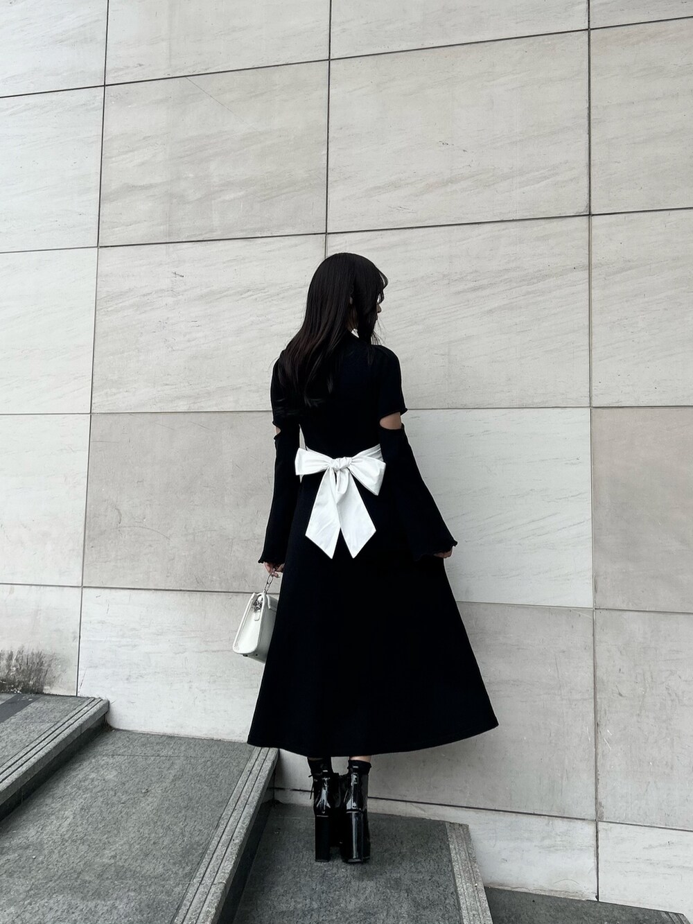 その他のブーツ、ブラック系のワンピース、ホワイト系のショルダーバッグを着用したレディースの冬コーディネートの3枚目の写真