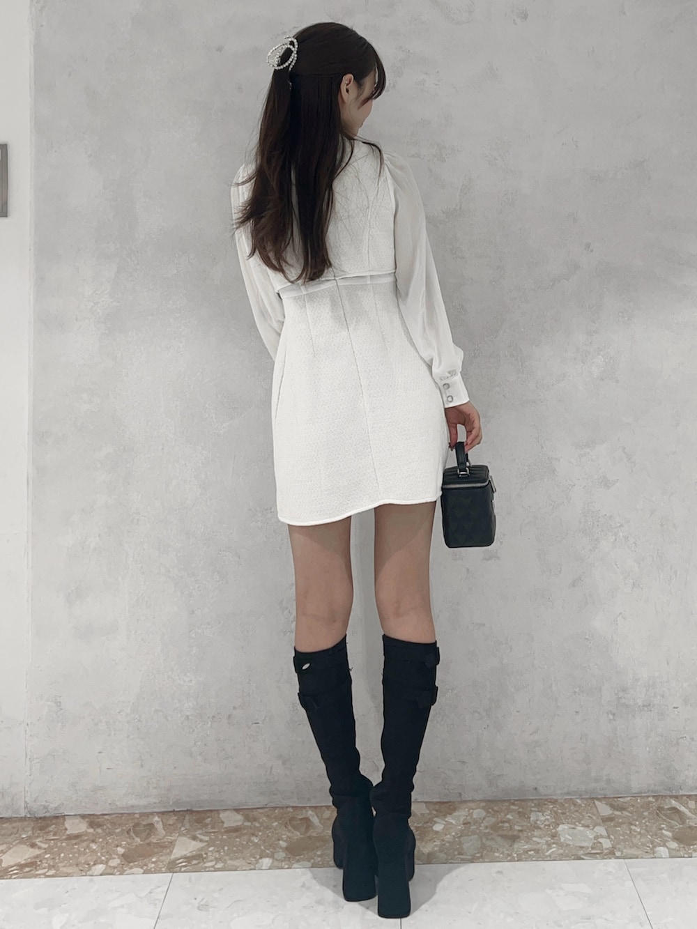 ホワイト系のワンピース、ブラック系のブーツ、ブラック系のハンドバッグを着用したレディースの秋コーディネートの3枚目の写真