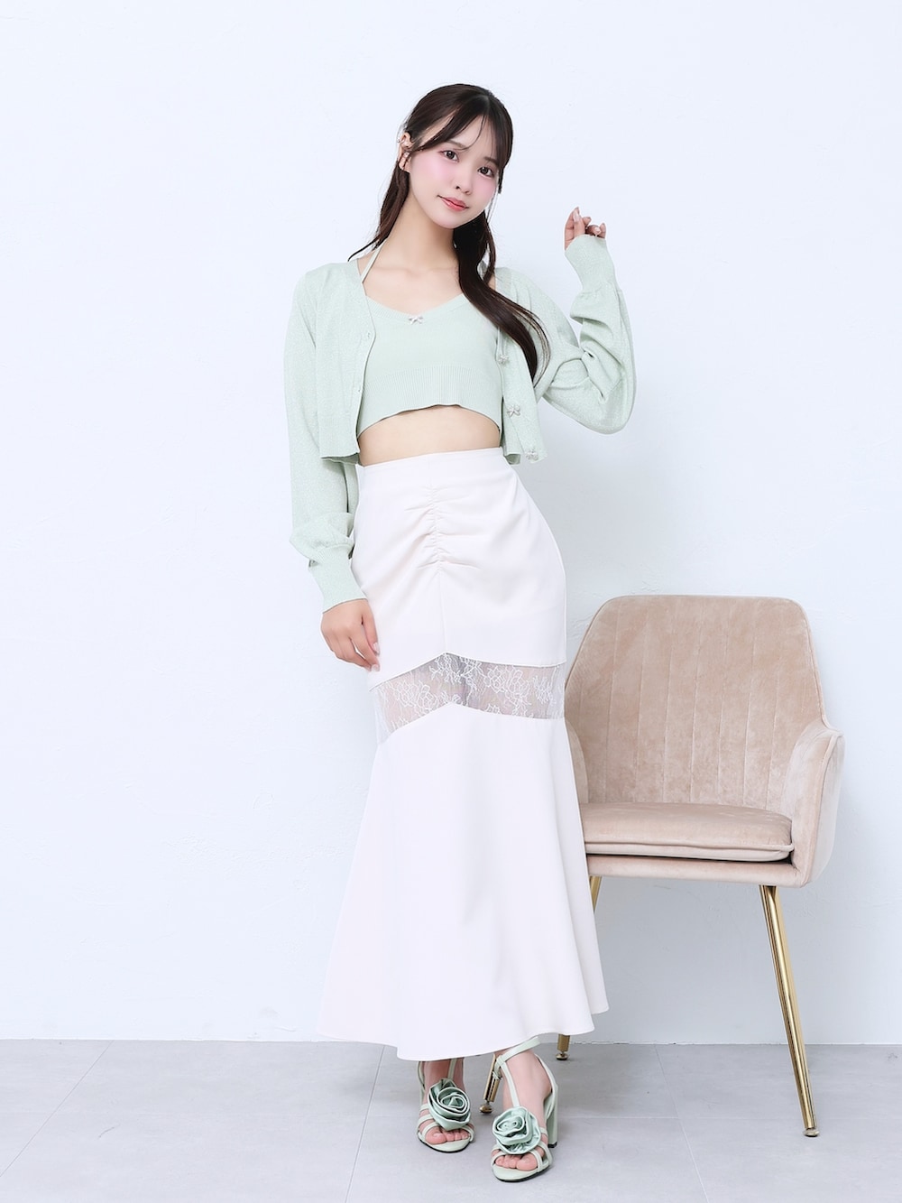 ホワイト系のスカート、グリーン系のニット/セーター、グリーン系のサンダルを着用したレディースの春コーディネートの2枚目の写真