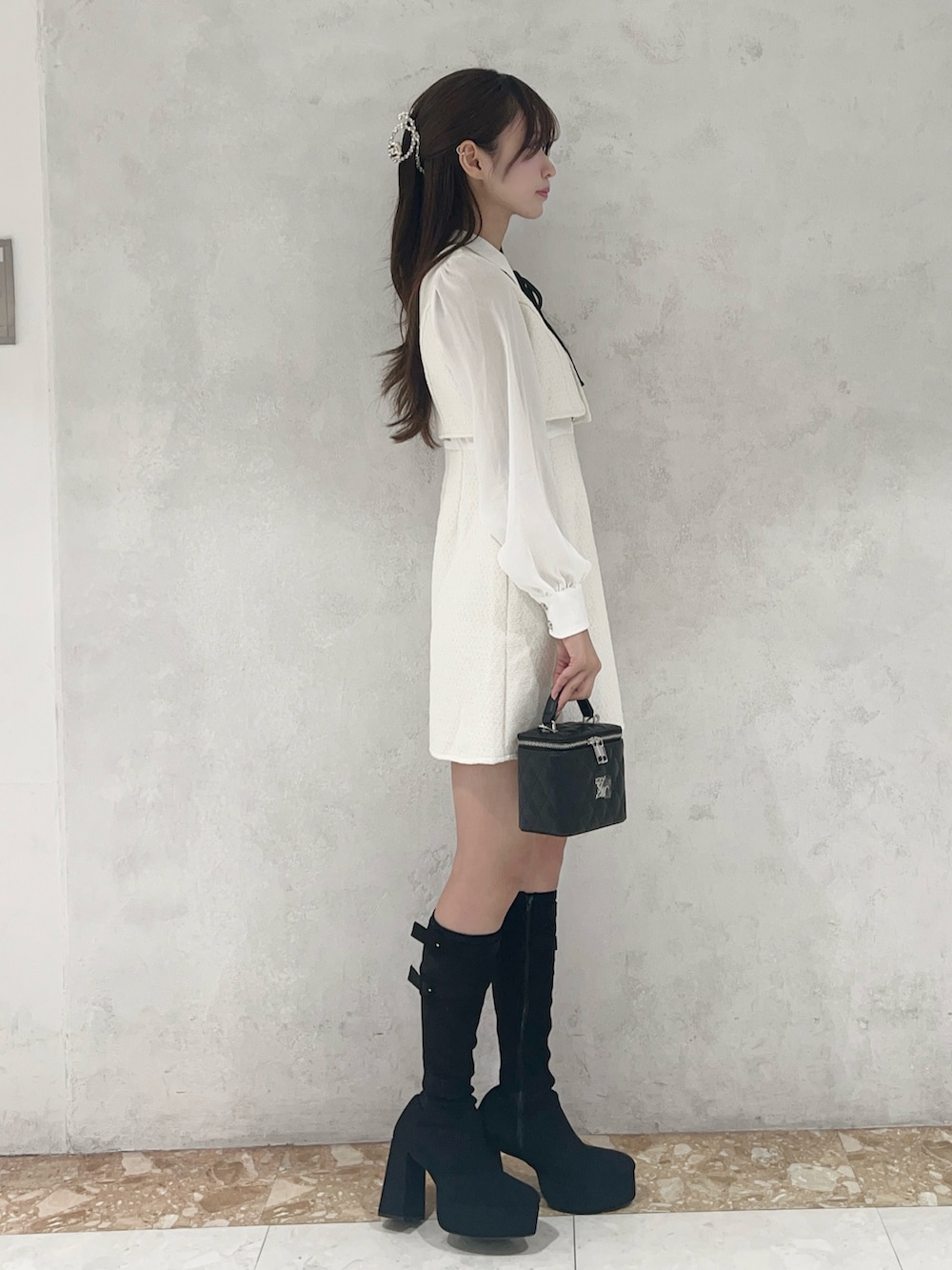 ホワイト系のワンピース、ブラック系のブーツ、ブラック系のハンドバッグを着用したレディースの秋コーディネートの2枚目の写真