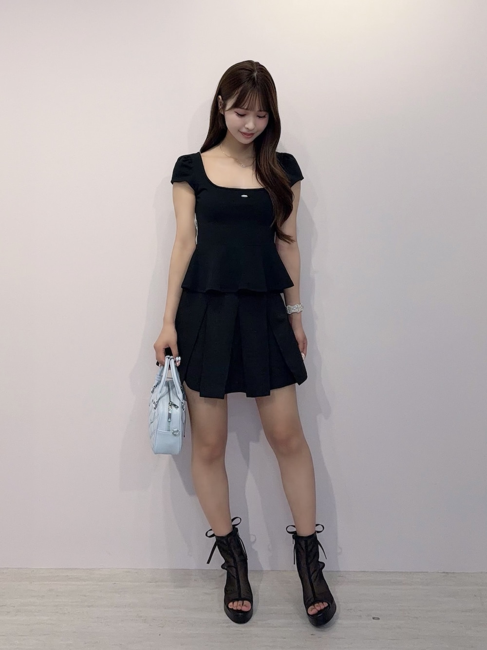 ブラック系のTシャツ/カットソー、ブラック系のスカート、ブラック系のハンドバッグを着用したレディースの春コーディネートの2枚目の写真