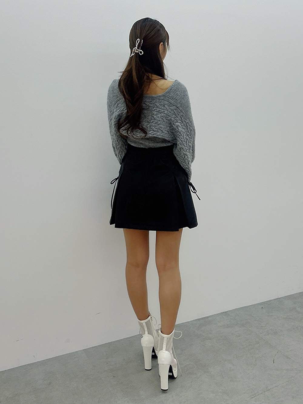 グレー系のニット/セーター、ブラック系のスカート、ホワイト系のブーツを着用したレディースの冬コーディネートの4枚目の写真