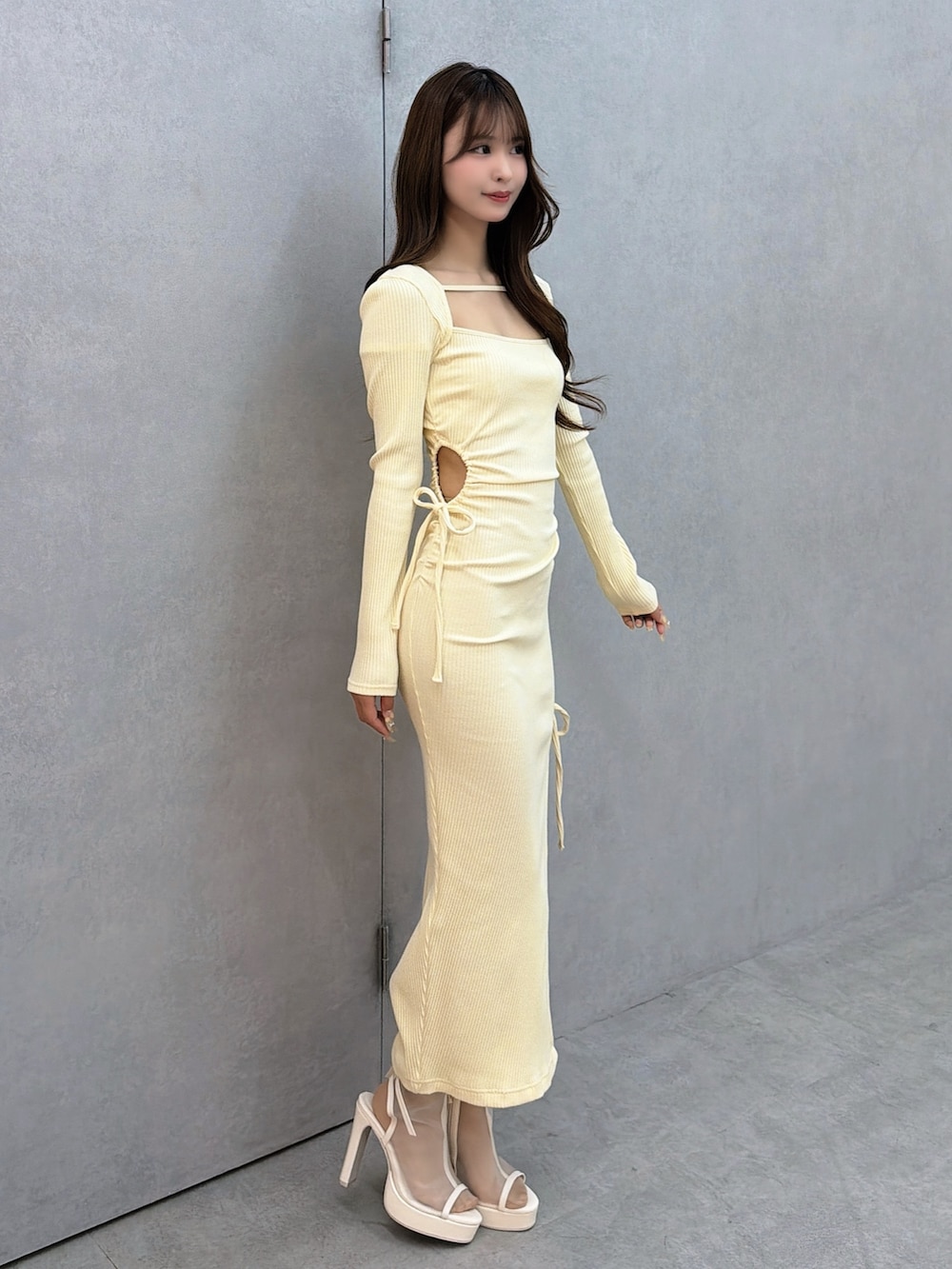 イエロー系のワンピース、ホワイト系のサンダルを着用したレディースの冬コーディネートの3枚目の写真