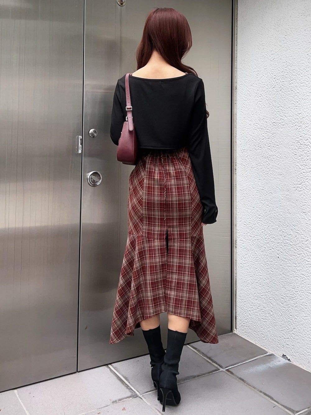 レッド系のワンピース、ブラック系のブーツ、レッド系のショルダーバッグを着用したレディースの秋コーディネートの3枚目の写真