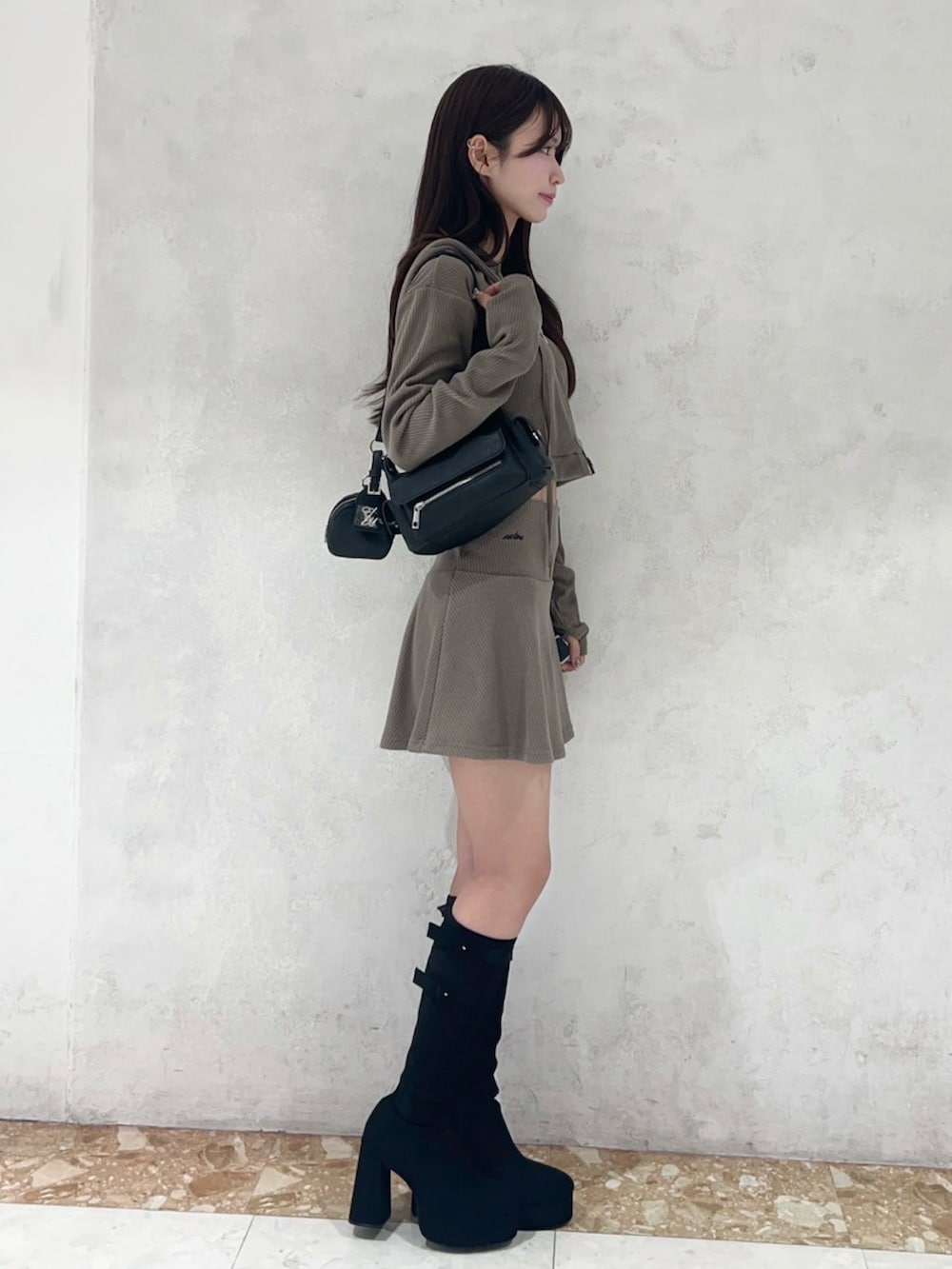 ブラウン系のパーカー、ブラウン系のスカート、ブラック系のブーツを着用したレディースの秋コーディネートの3枚目の写真