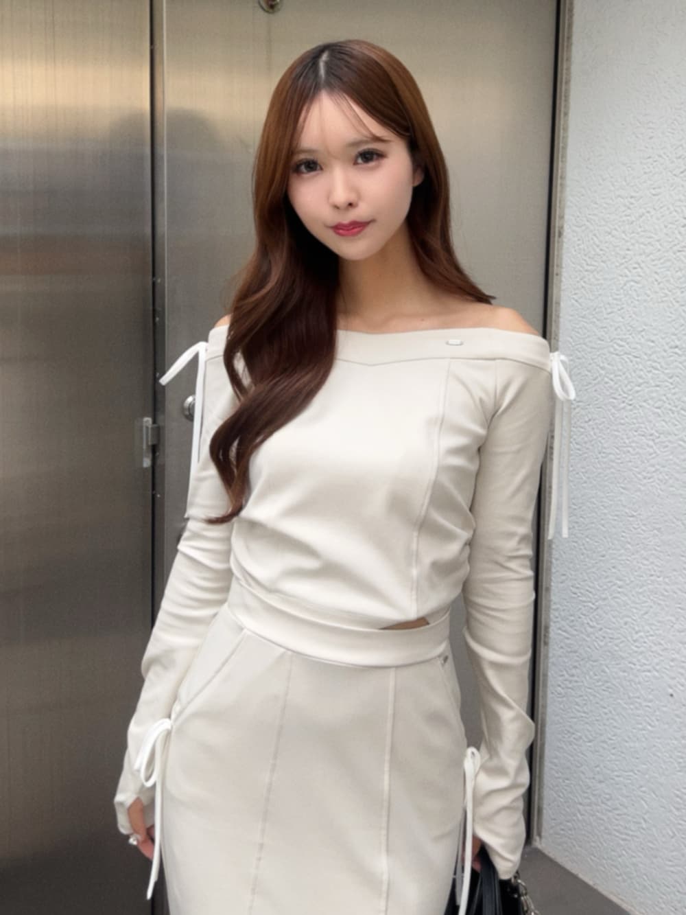 ホワイト系のTシャツ/カットソー、ホワイト系のスカート、ブラック系のハンドバッグを着用したレディースの秋コーディネートの4枚目の写真