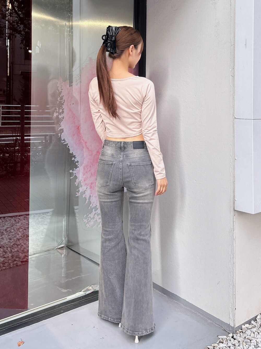 ブラック系のデニムパンツ、ピンク系のTシャツ/カットソー、ホワイト系のサンダルを着用したレディースの秋コーディネートの4枚目の写真