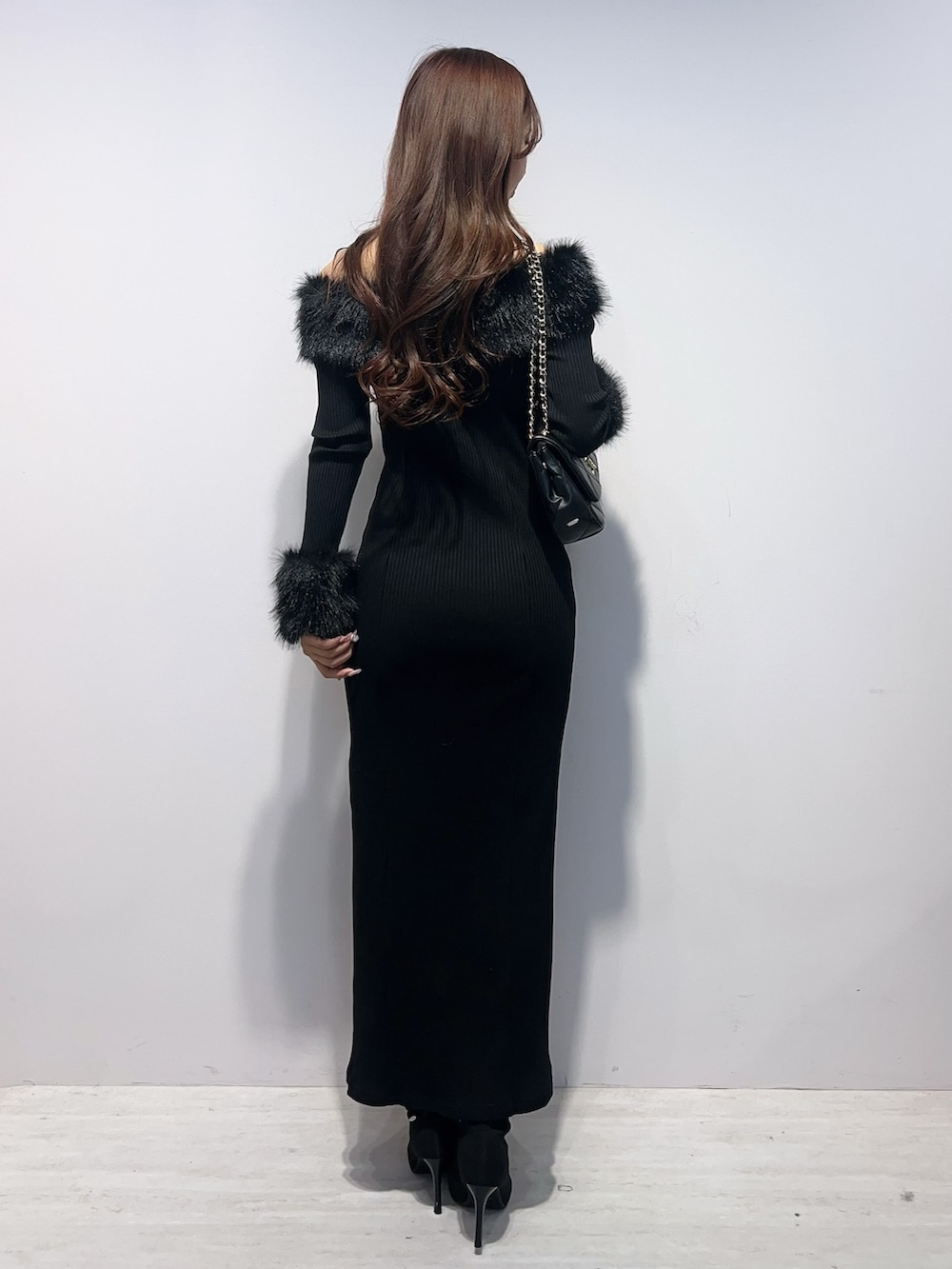 ブラック系のワンピース、ブラック系のブーツ、ブラック系のハンドバッグを着用したレディースの秋コーディネートの4枚目の写真