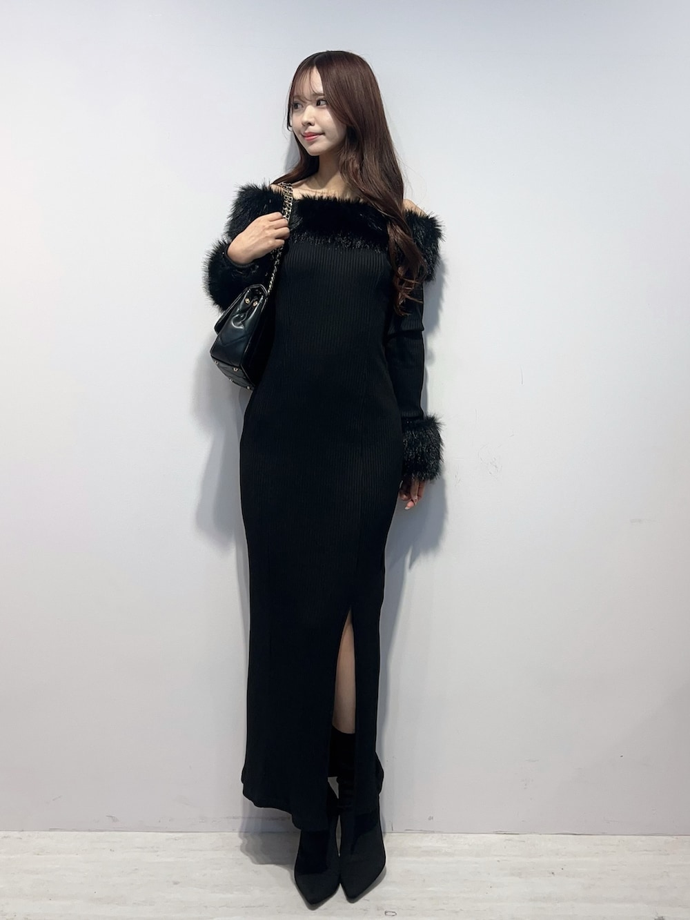 ブラック系のワンピース、ブラック系のブーツ、ブラック系のハンドバッグを着用したレディースの秋コーディネートの2枚目の写真