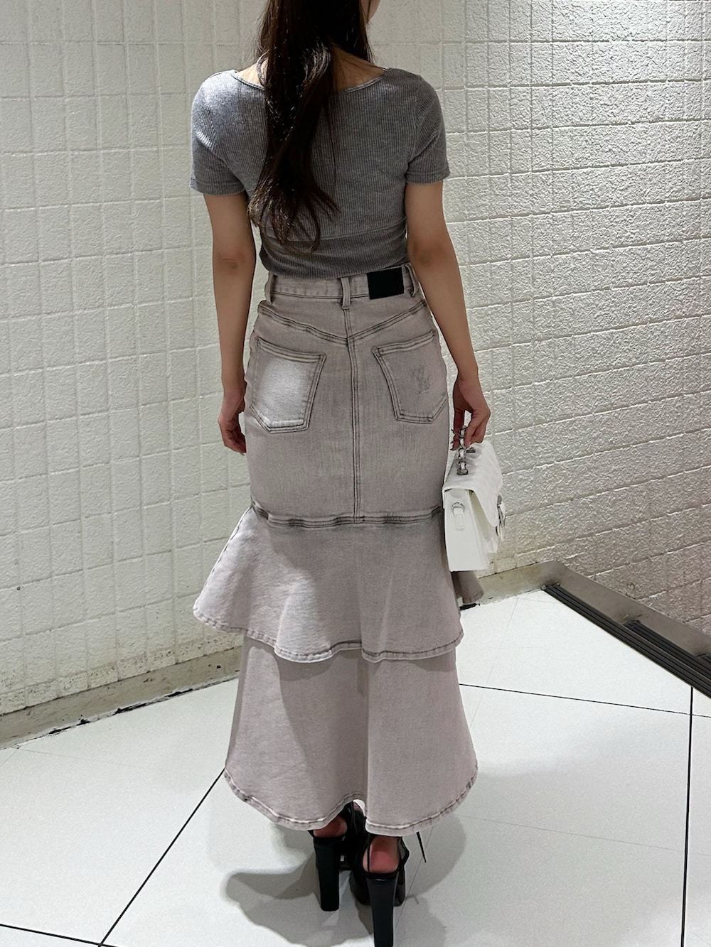 ピンク系のデニムスカート、グレー系のTシャツ/カットソー、ブラック系のサンダルを着用したレディースの秋コーディネートの3枚目の写真