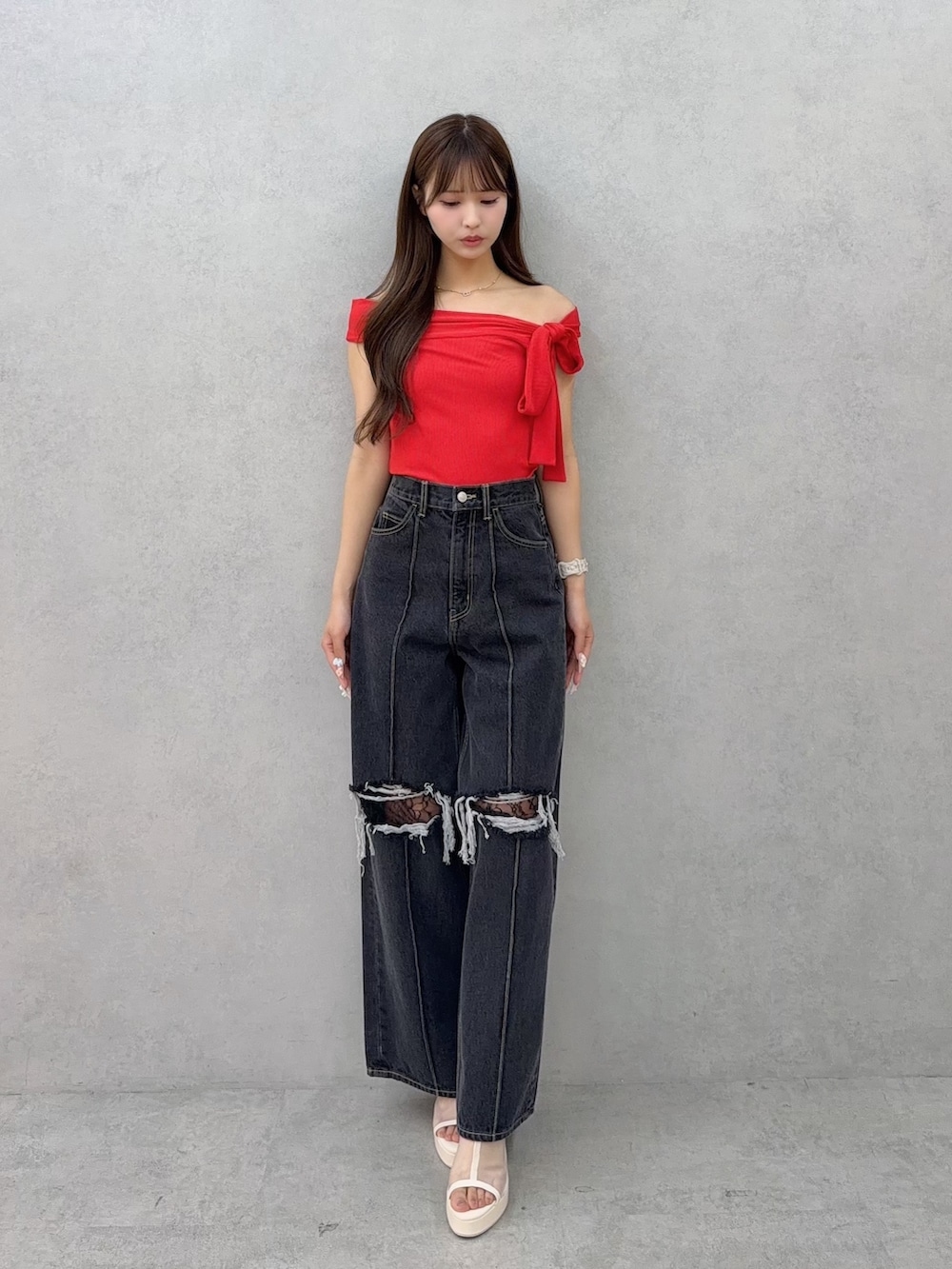 ブラック系のデニムパンツ、レッド系のTシャツ/カットソー、ホワイト系のサンダルを着用したレディースの春コーディネートの2枚目の写真
