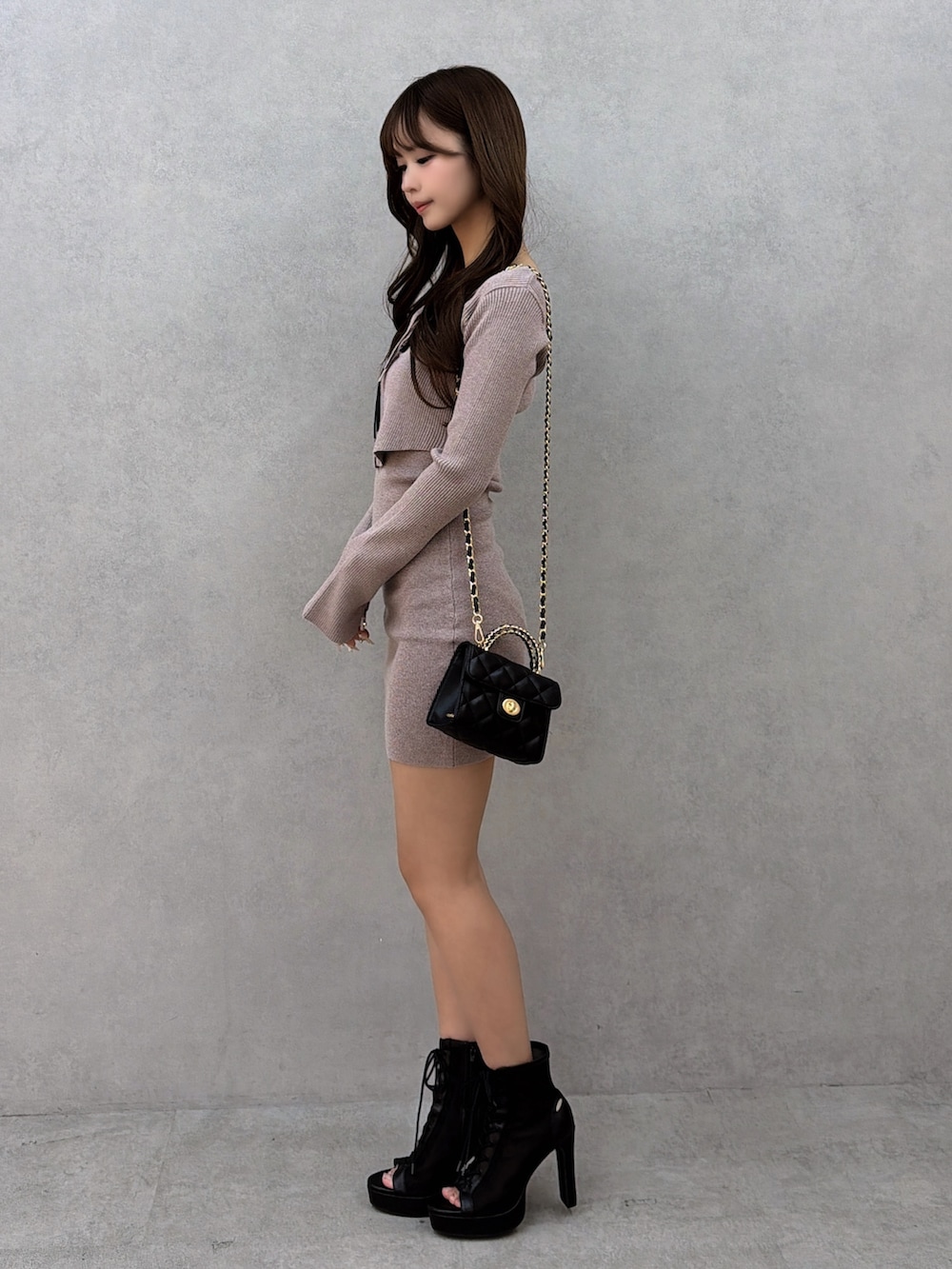 ベージュ系のワンピース、ブラック系のハンドバッグ、ブラック系のブーツを着用したレディースの冬コーディネートの3枚目の写真