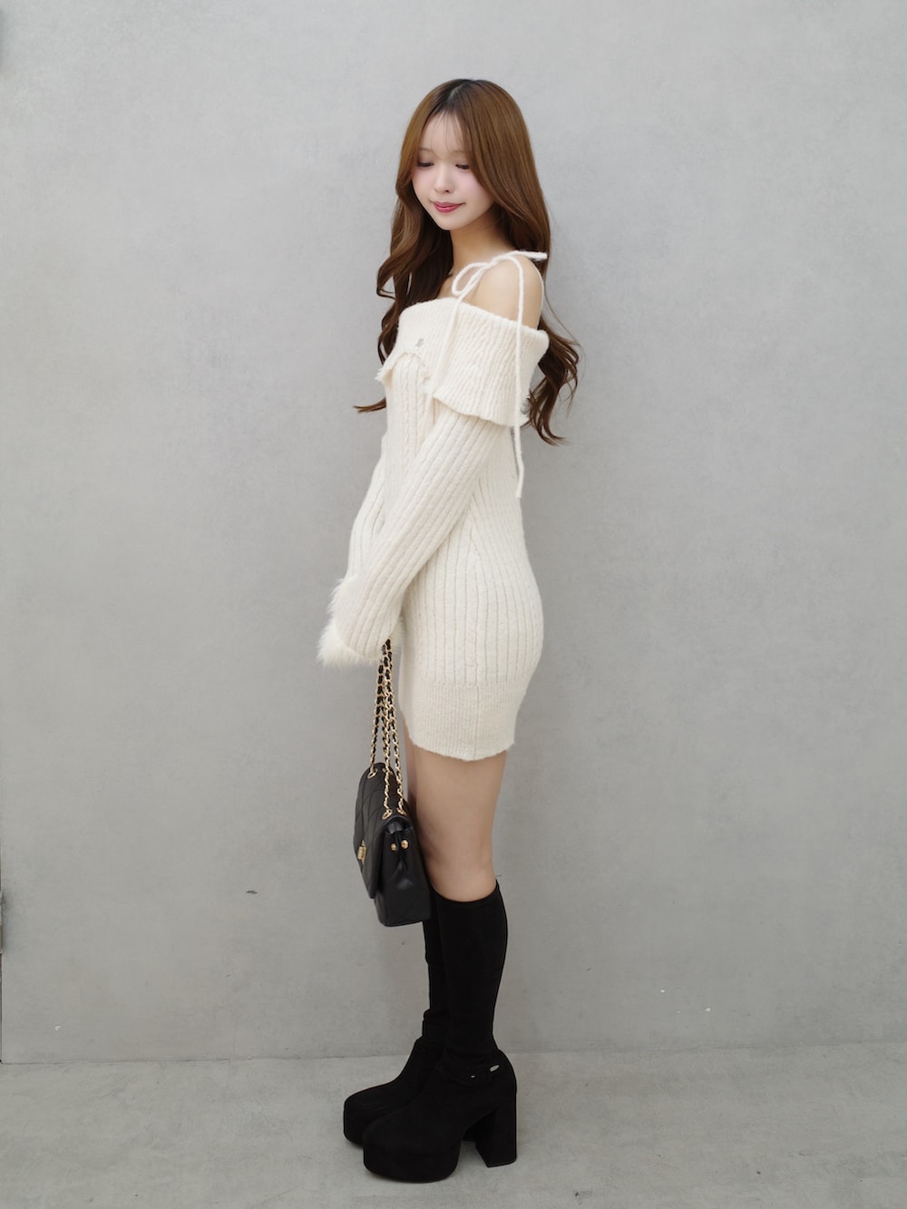 ホワイト系のワンピース、ブラック系のブーツ、ブラック系のハンドバッグを着用したレディースの秋コーディネートの2枚目の写真