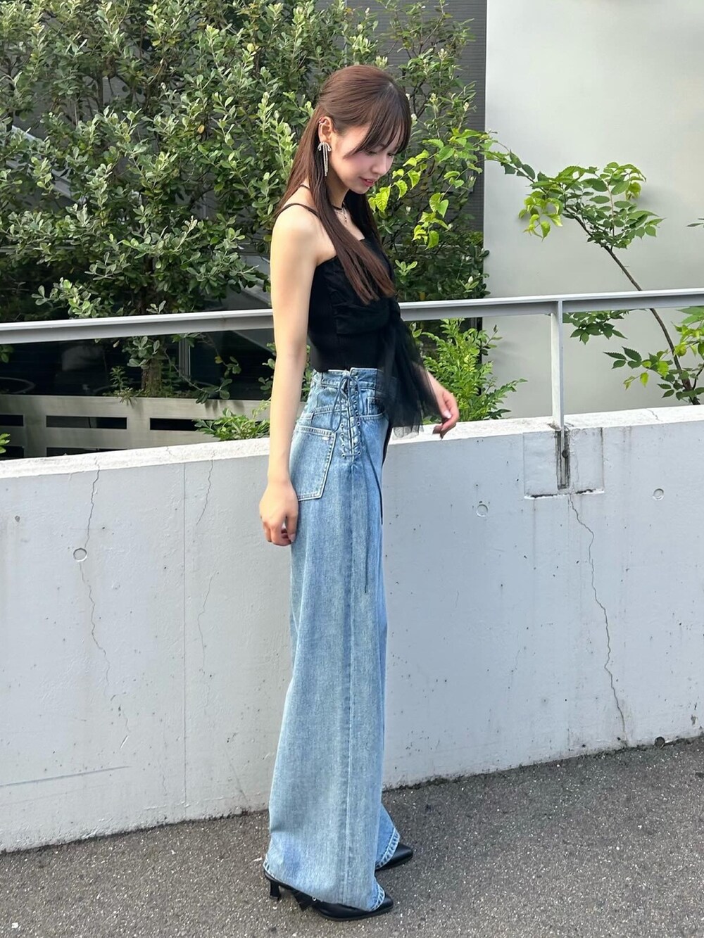ブラック系のキャミソール、ブルー系のデニムパンツ、ブラック系のパンプスを着用したレディースの夏コーディネートの2枚目の写真