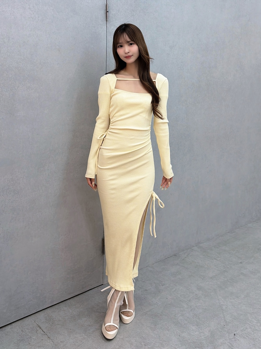 イエロー系のワンピース、ホワイト系のサンダルを着用したレディースの冬コーディネートの2枚目の写真