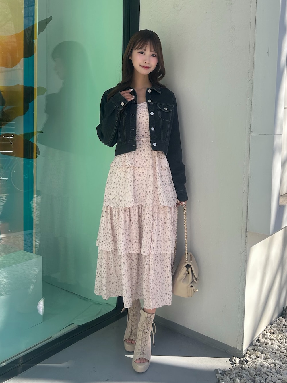 ピンク系のワンピース、ブラック系のデニムジャケット、ベージュ系のバックパック/リュックを着用したレディースの春コーディネートの2枚目の写真