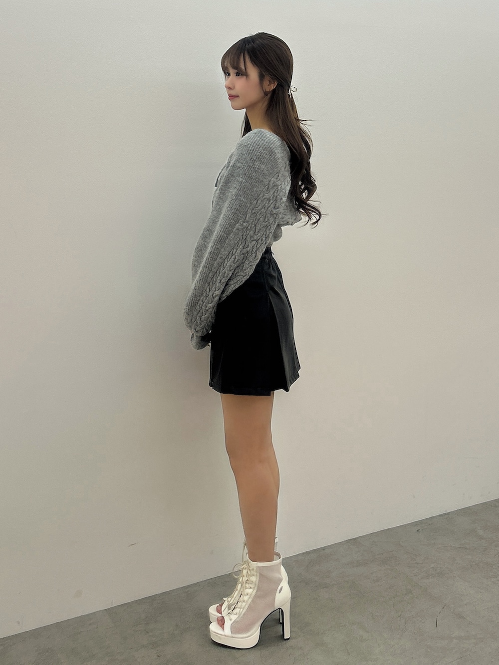 グレー系のニット/セーター、ブラック系のスカート、ホワイト系のブーツを着用したレディースの冬コーディネートの3枚目の写真