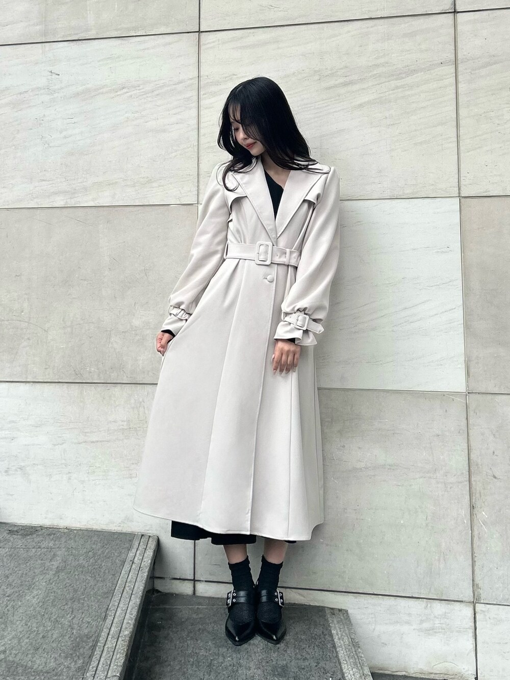 ブラック系のワンピース、ブラック系のパンプス、ベージュ系のトレンチコートを着用したレディースの冬コーディネートの2枚目の写真