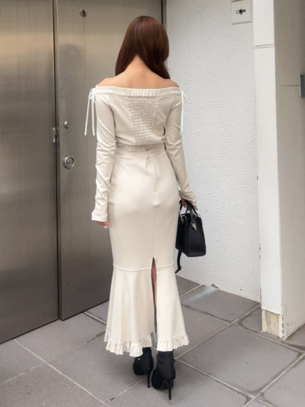 ホワイト系のTシャツ/カットソー、ホワイト系のスカート、ブラック系のハンドバッグを着用したレディースの秋コーディネートの3枚目の写真