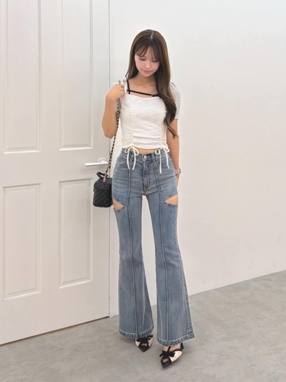 ブルー系のデニムパンツ、ブラック系のハンドバッグ、その他のパンプスを着用したレディースの夏コーディネートの2枚目の写真
