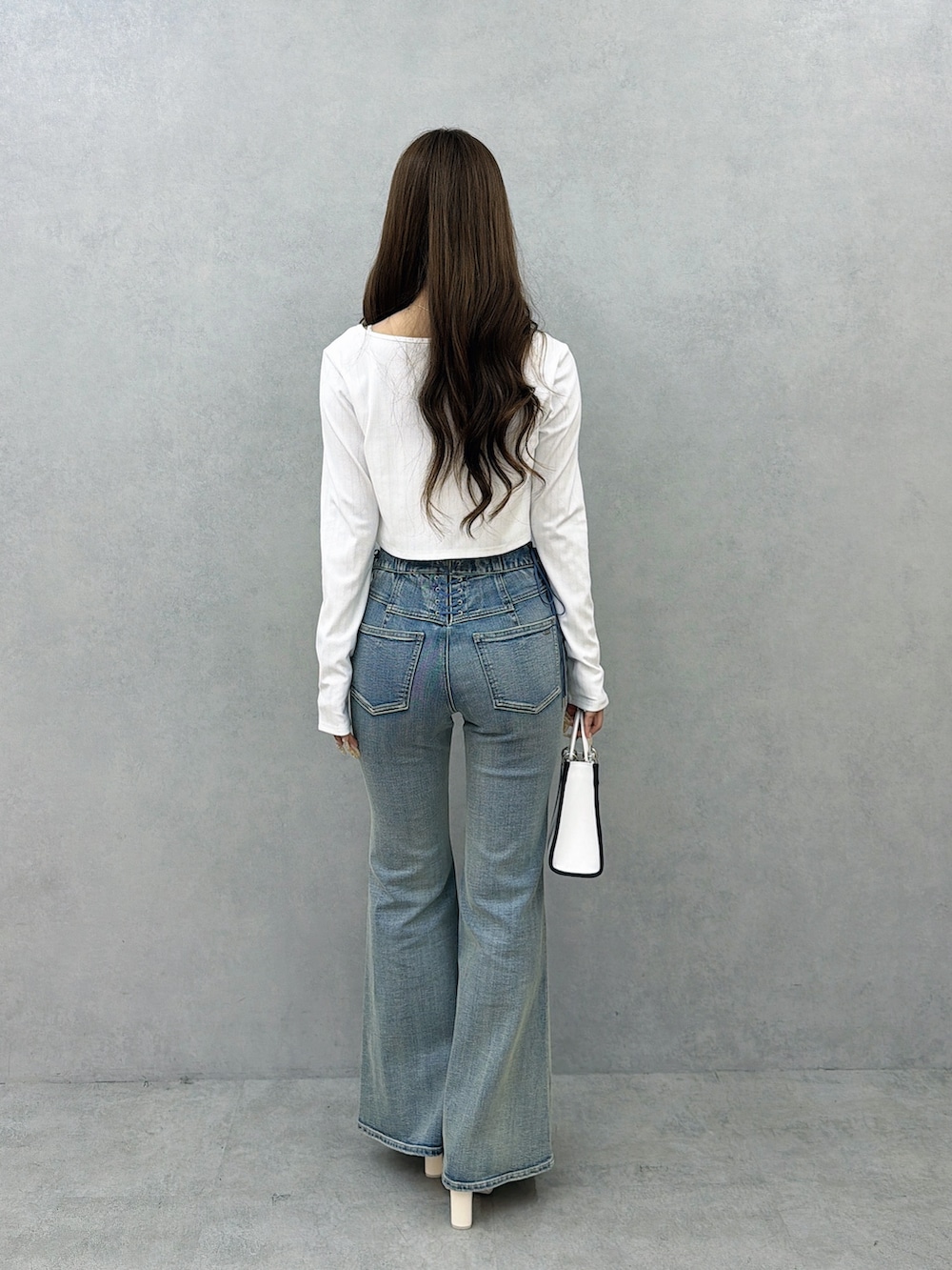ブルー系のデニムパンツ、ホワイト系のサンダル、ホワイト系のショルダーバッグを着用したレディースの春コーディネートの4枚目の写真