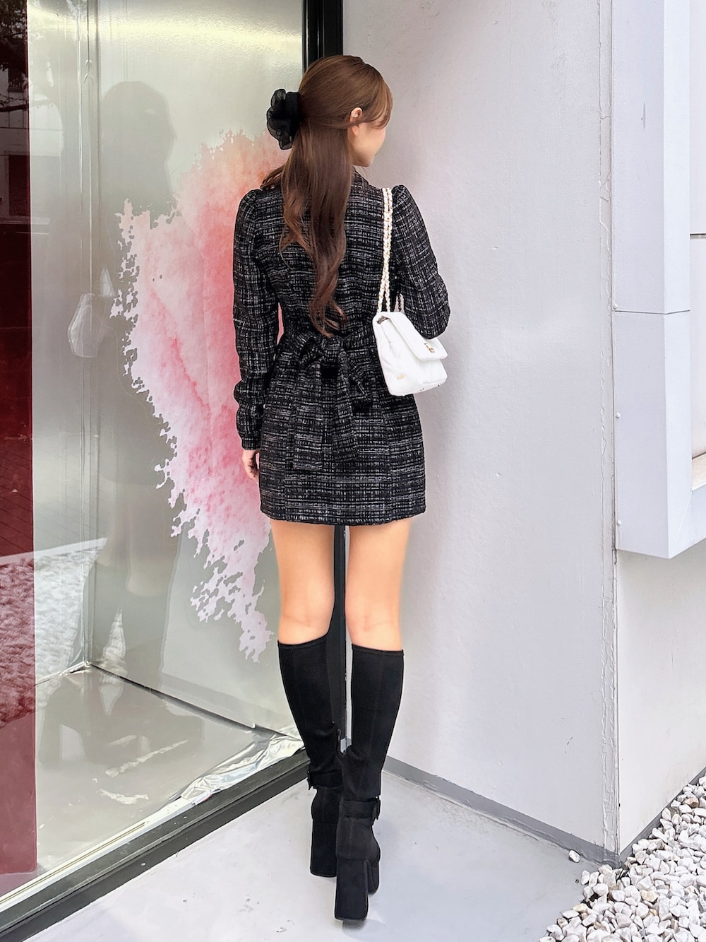 ブラック系のワンピース、ホワイト系のハンドバッグ、ブラック系のブーツを着用したレディースの秋コーディネートの4枚目の写真