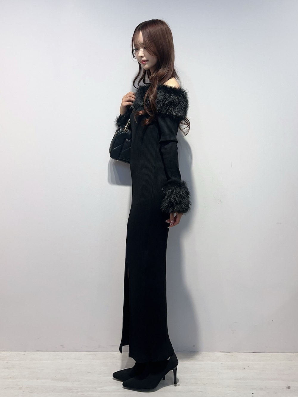 ブラック系のワンピース、ブラック系のブーツ、ブラック系のハンドバッグを着用したレディースの秋コーディネートの3枚目の写真