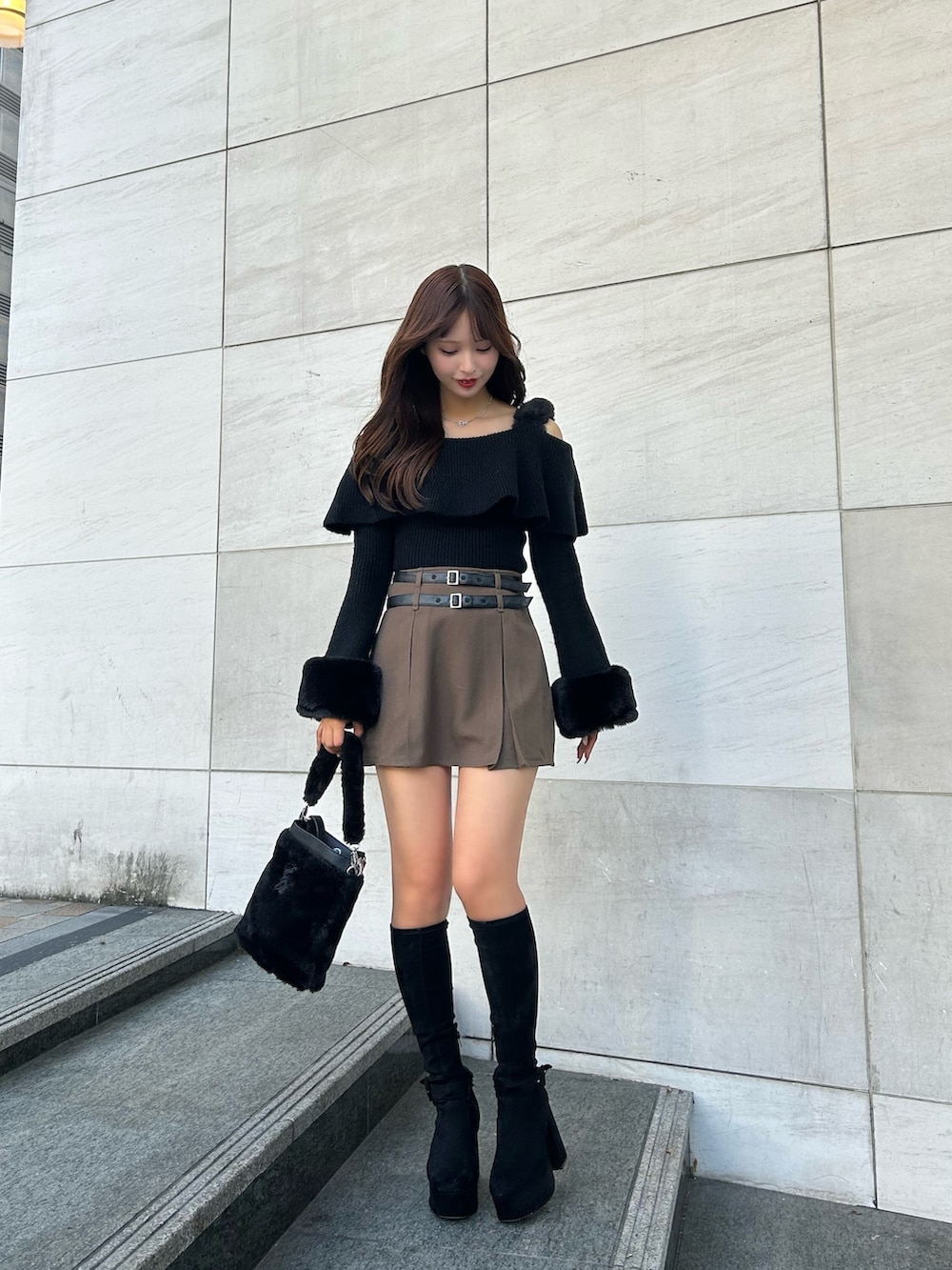 ブラック系のニット/セーター、ブラウン系のスカート、ブラック系のショルダーバッグを着用したレディースの秋コーディネートの2枚目の写真
