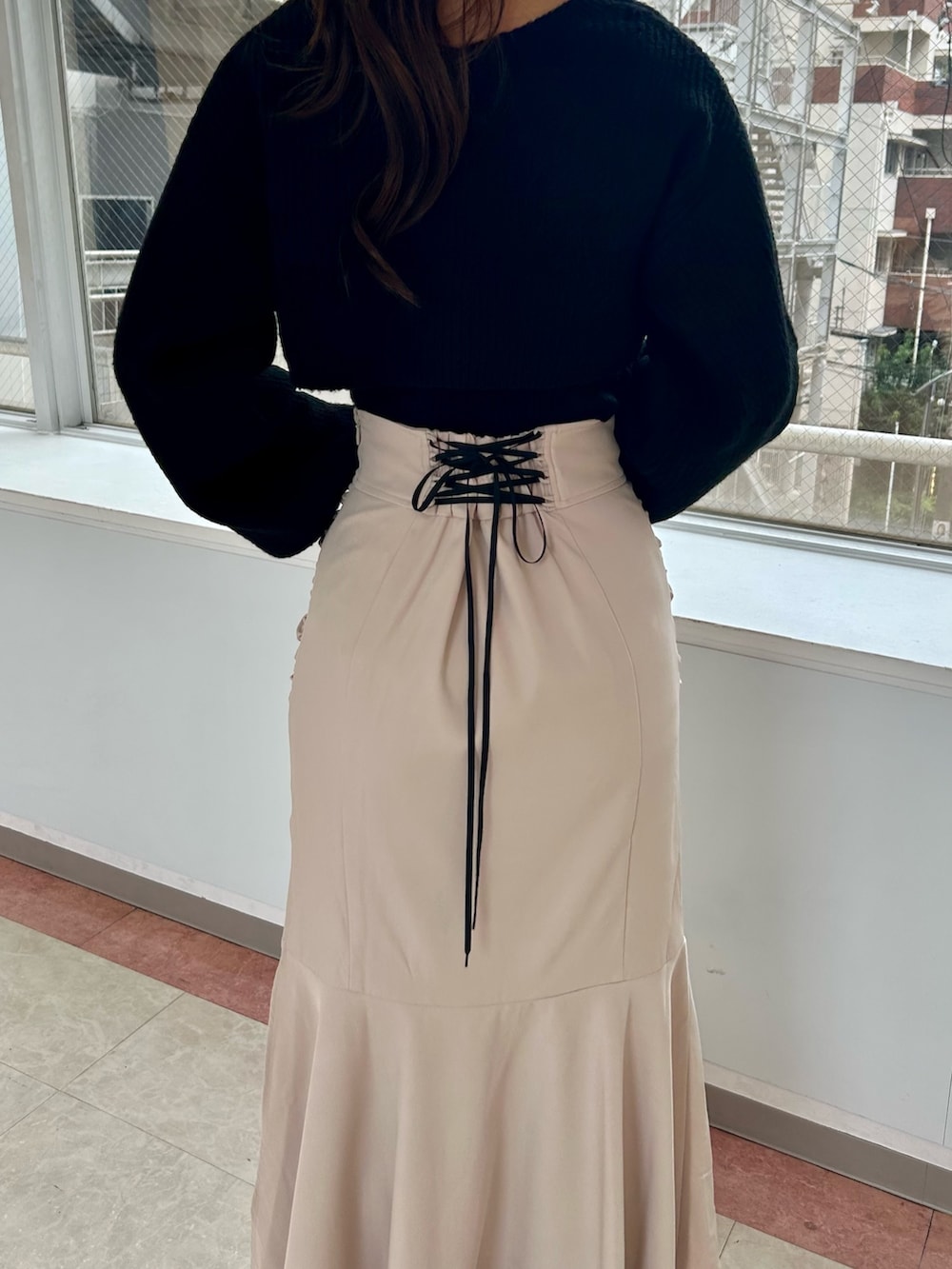 ベージュ系のスカート、ブラック系のニット/セーター、ブラック系のショルダーバッグを着用したレディースの秋コーディネートの3枚目の写真