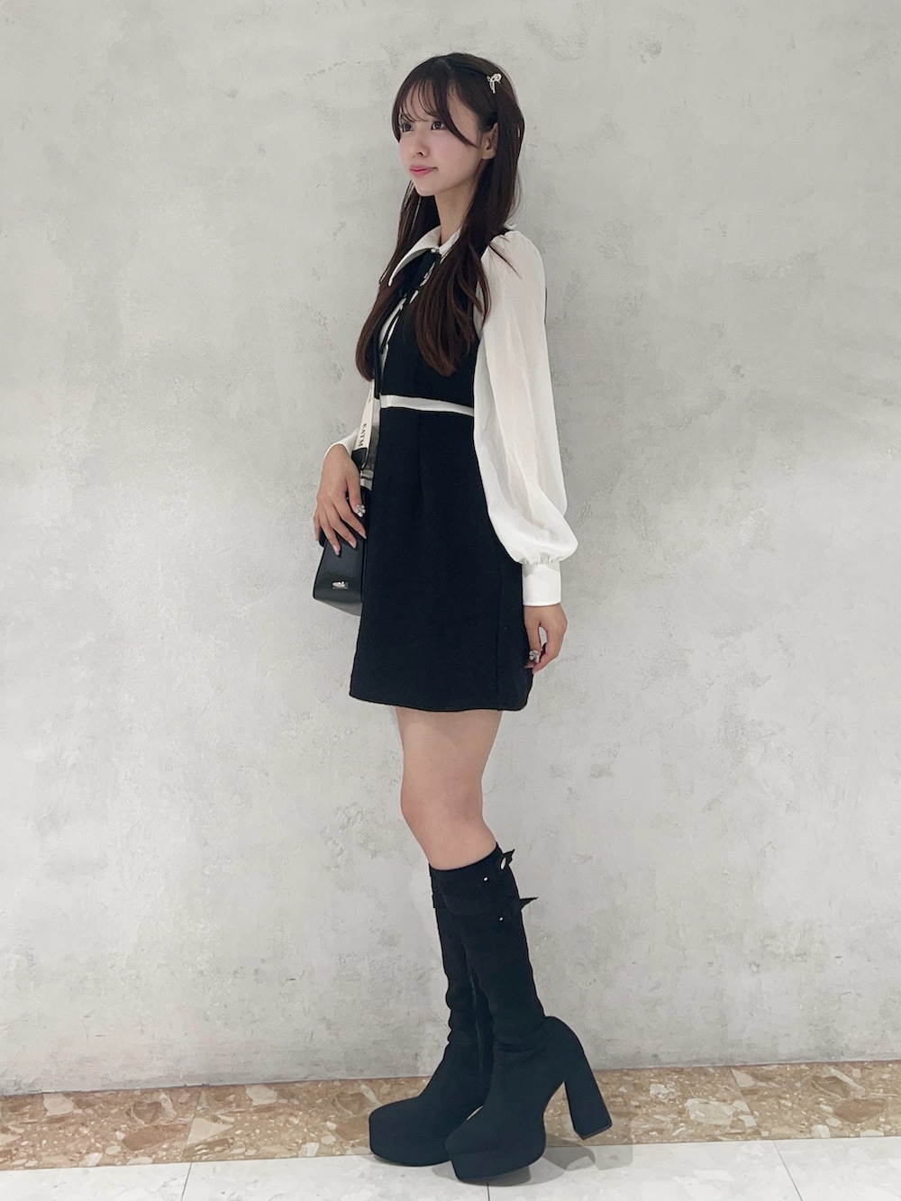 ブラック系のショルダーバッグ、ブラック系のワンピース、ブラック系のブーツを着用したレディースの秋コーディネートの2枚目の写真