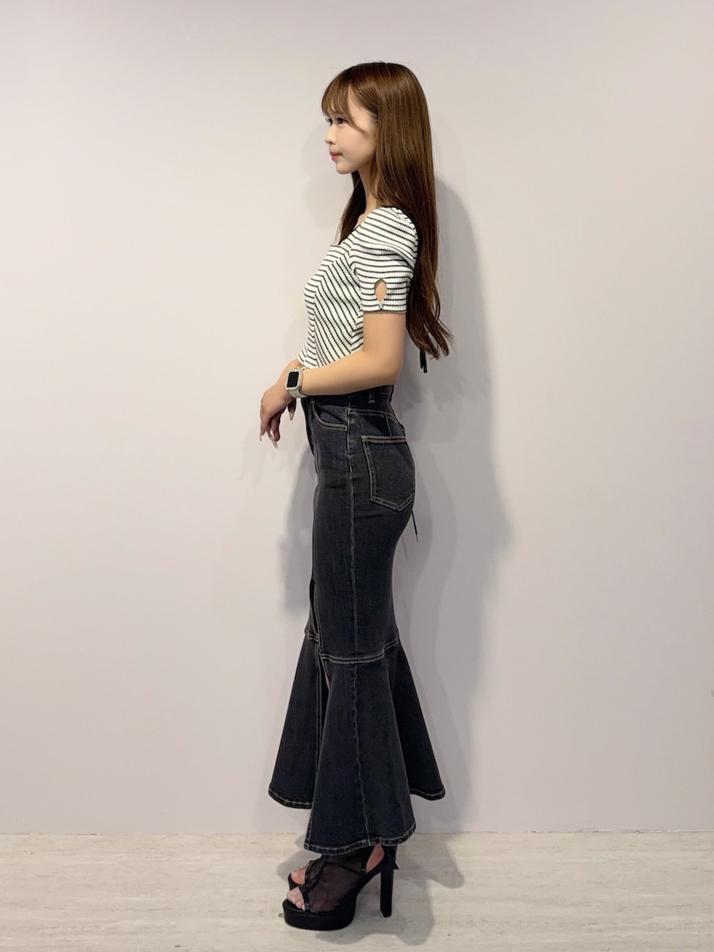 ブラック系のデニムスカート、その他のTシャツ/カットソー、ブラック系のサンダルを着用したレディースの春コーディネートの3枚目の写真